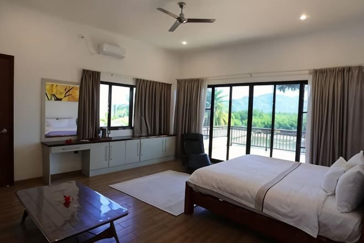 Une chambre d’hôtel avec un lit, un bureau, une chaise et un balcon offrant une vue.