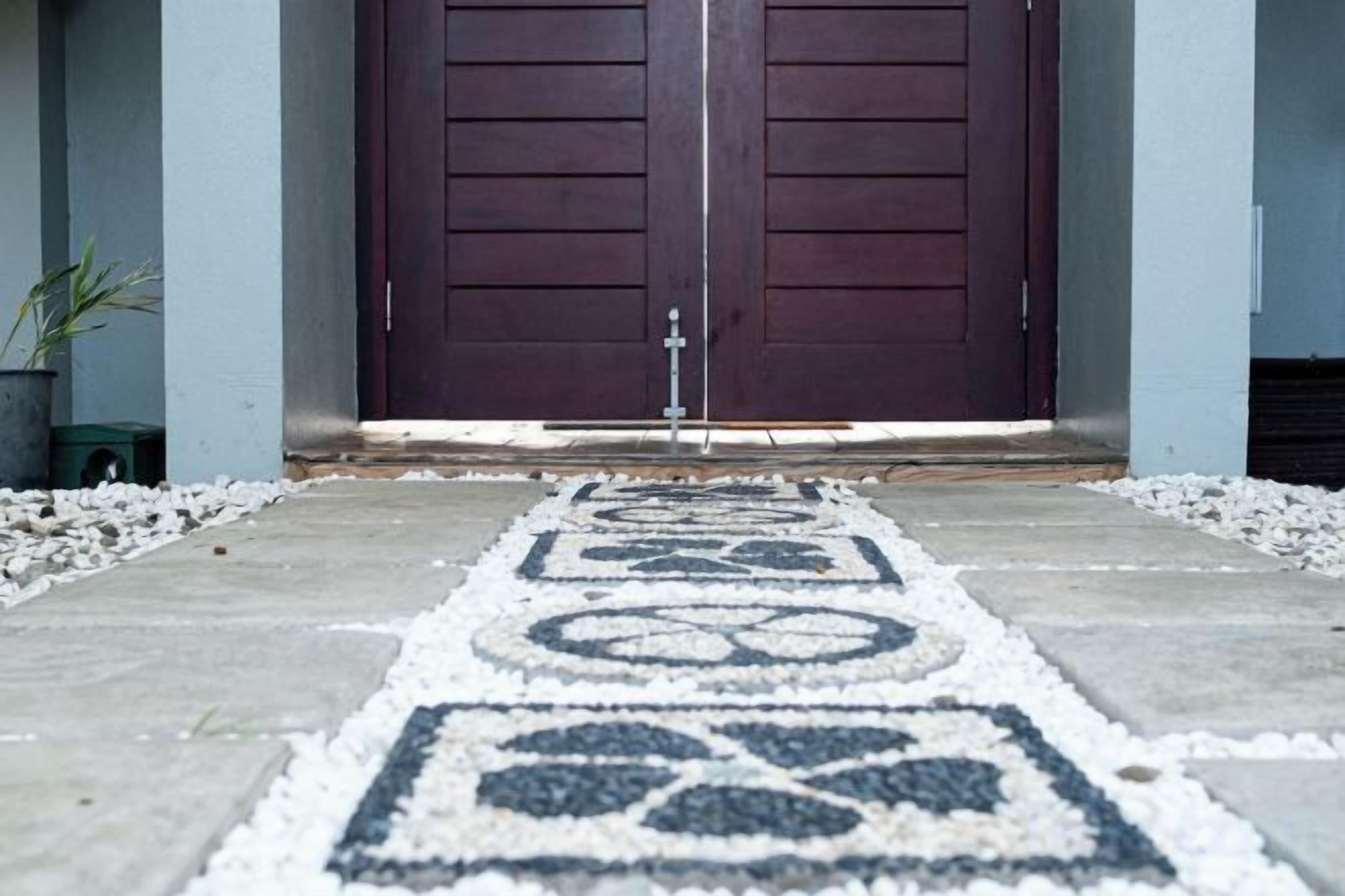 A double door entrance with a patterned floor leading up to it.