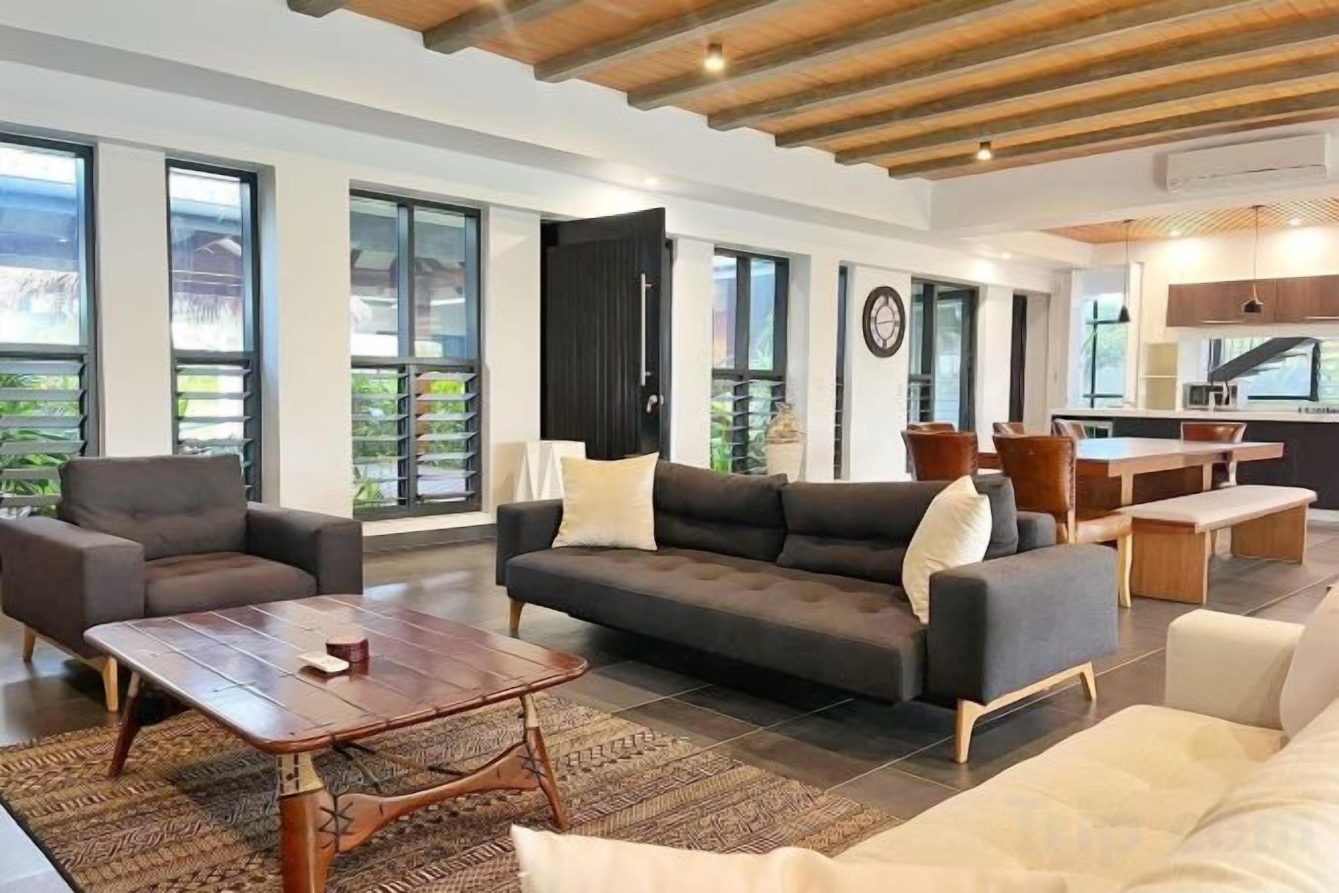 A modern living room with a sofa set, a coffee table, and a dining area with a table and chairs.