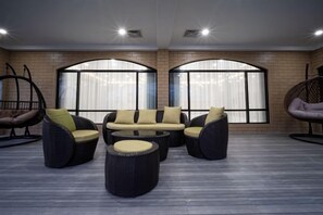 A lounge area with a sofa set, round coffee table, and hanging chairs. - Naisoso Island Villas - Fiji (Viti Levu)