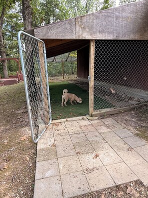 A fenced outdoor area with a wooden shelter, a paved walkway, and a grassy patch. - Guest house, convenient setting, large wooded lot of towering oaks (Hollister)