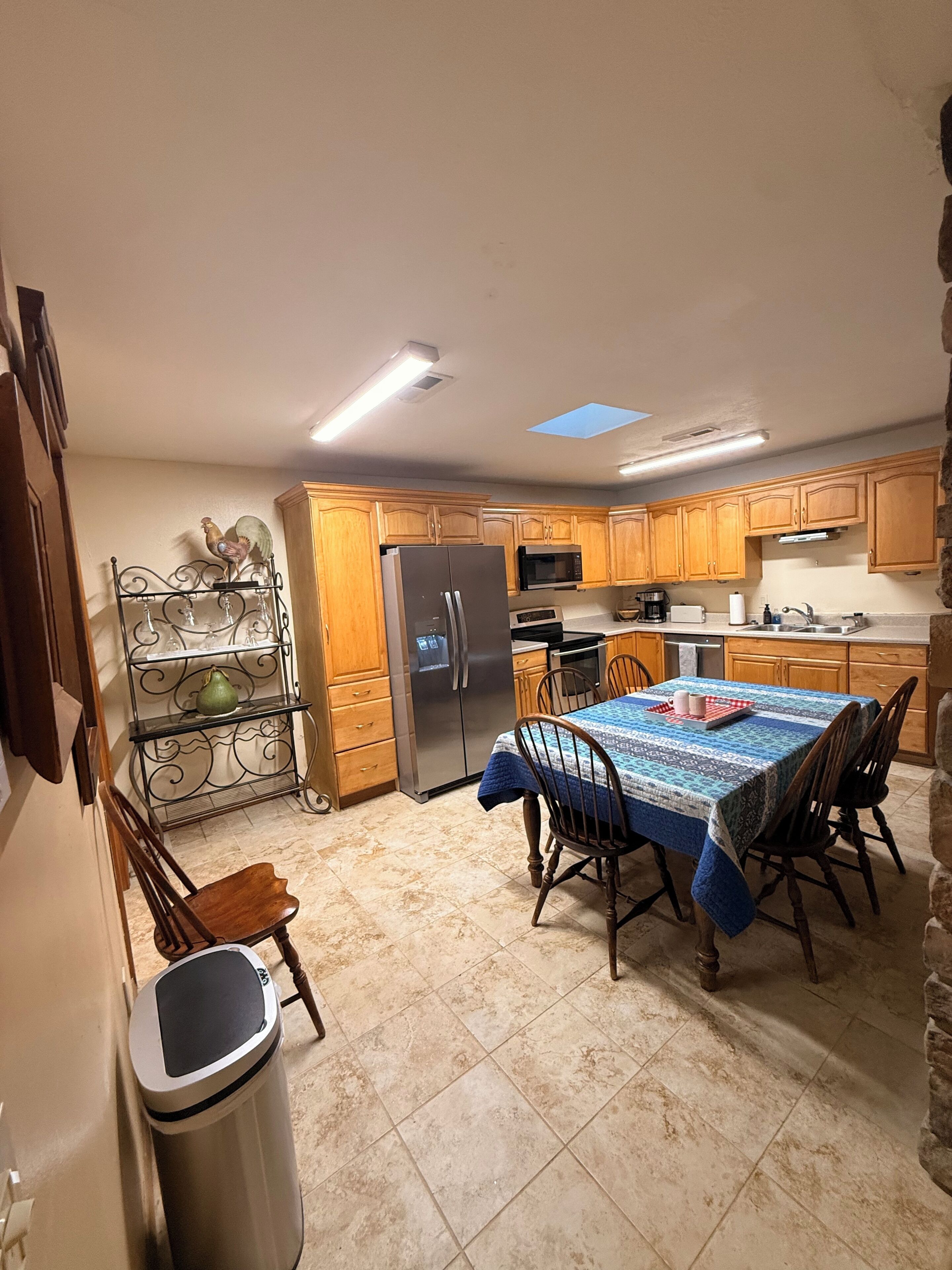 A kitchen with wooden cabinets, a stainless steel refrigerator, a microwave, and a dining table with chairs.