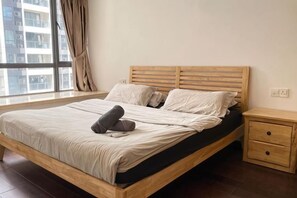 A bed with a wooden frame, a bedside table with drawers, and a window with curtains. - R&F Princess Cove Boutique Homestay By TREX #Nearby CIQ #Johor Bahru #JB Central (Johor Bahru)
