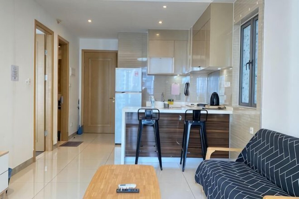 A modern kitchen with a central island, a dining area with a wooden table, and a sofa.