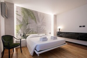 Een moderne slaapkamer met een bed, nachtkastje, stoel en een wanddecoratie.