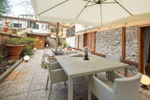 An outdoor patio with a table and chairs, surrounded by potted plants and a stone wall. - Ponte Rosso Modern (Florence)