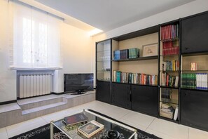 Een moderne woonkamer met een flatscreen televisie, een boekenkast en een salontafel.