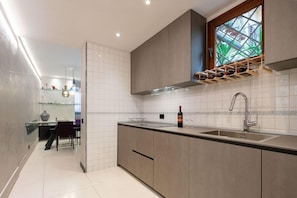 A modern kitchen with a built-in wine rack, a large window with a view, and a dining area in the background.