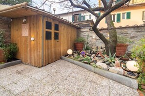 A wooden structure with a tiled patio, surrounded by potted plants and rocks. - Ponte Rosso Modern (Florence)