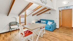 Et moderne interiør med et spiseområde, en blå sofa og et træloft.