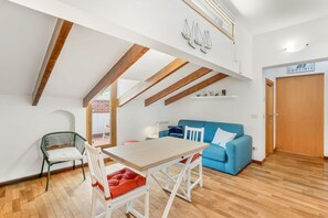 Ein modernes Interieur mit Essbereich, einem blauen Sofa und einer Holzzieldecke.