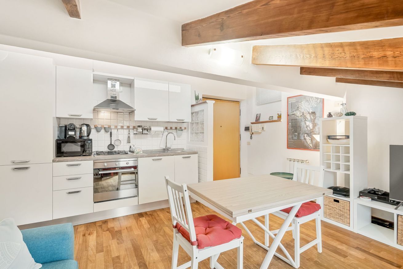 A compact kitchen with white cabinetry, a wooden dining table, and a blue chair.