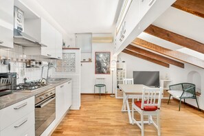 Una cocina moderna con armarios blancos, una estufa a gas y un comedor con mesa y sillas.