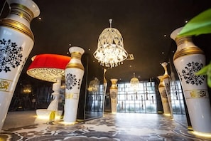 Un hall d’hôtel agrémenté de colonnes richement décorées, d’un lustre et d’un sol à motifs.