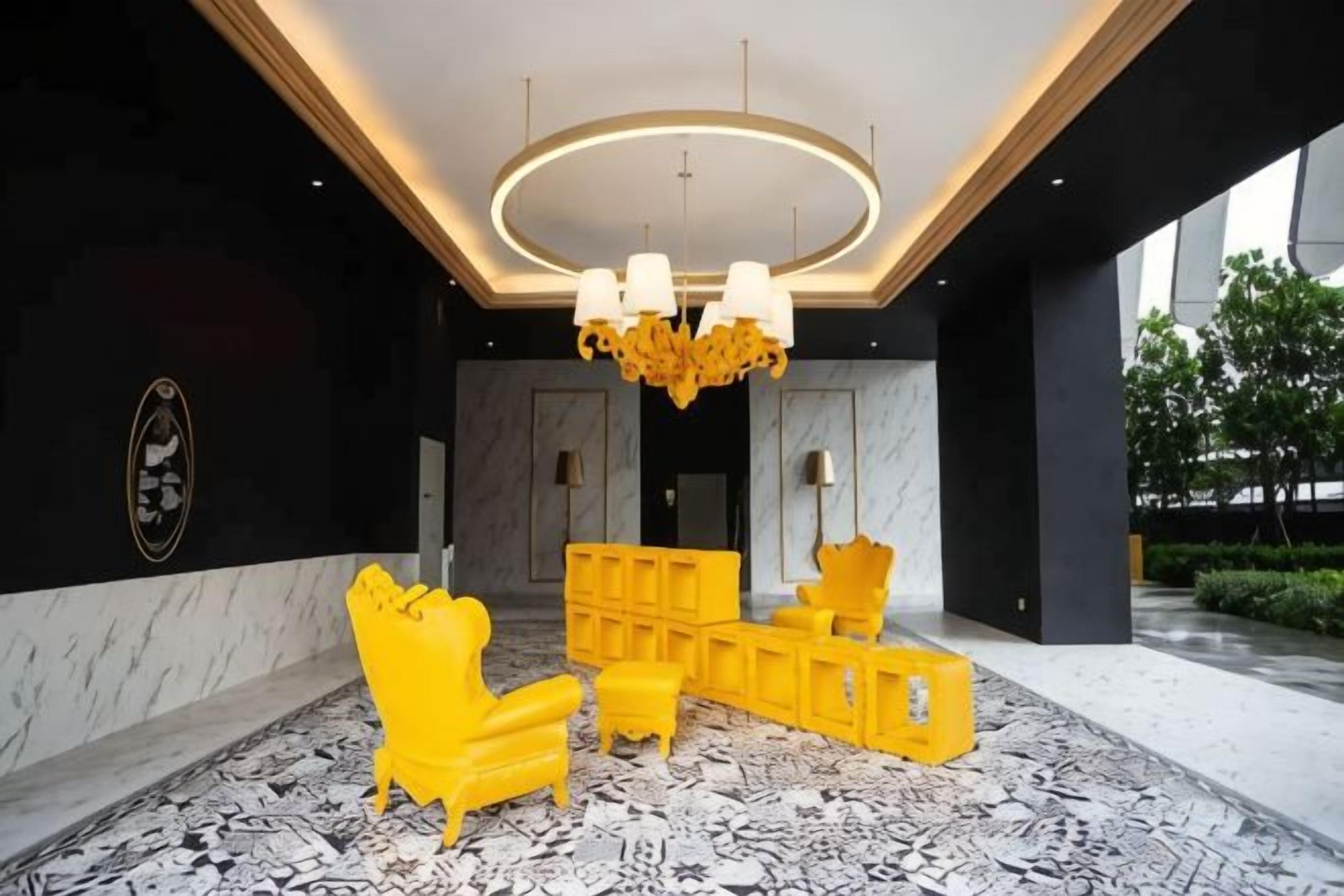 A lobby with a chandelier, yellow furniture, marble walls, and a patterned floor.