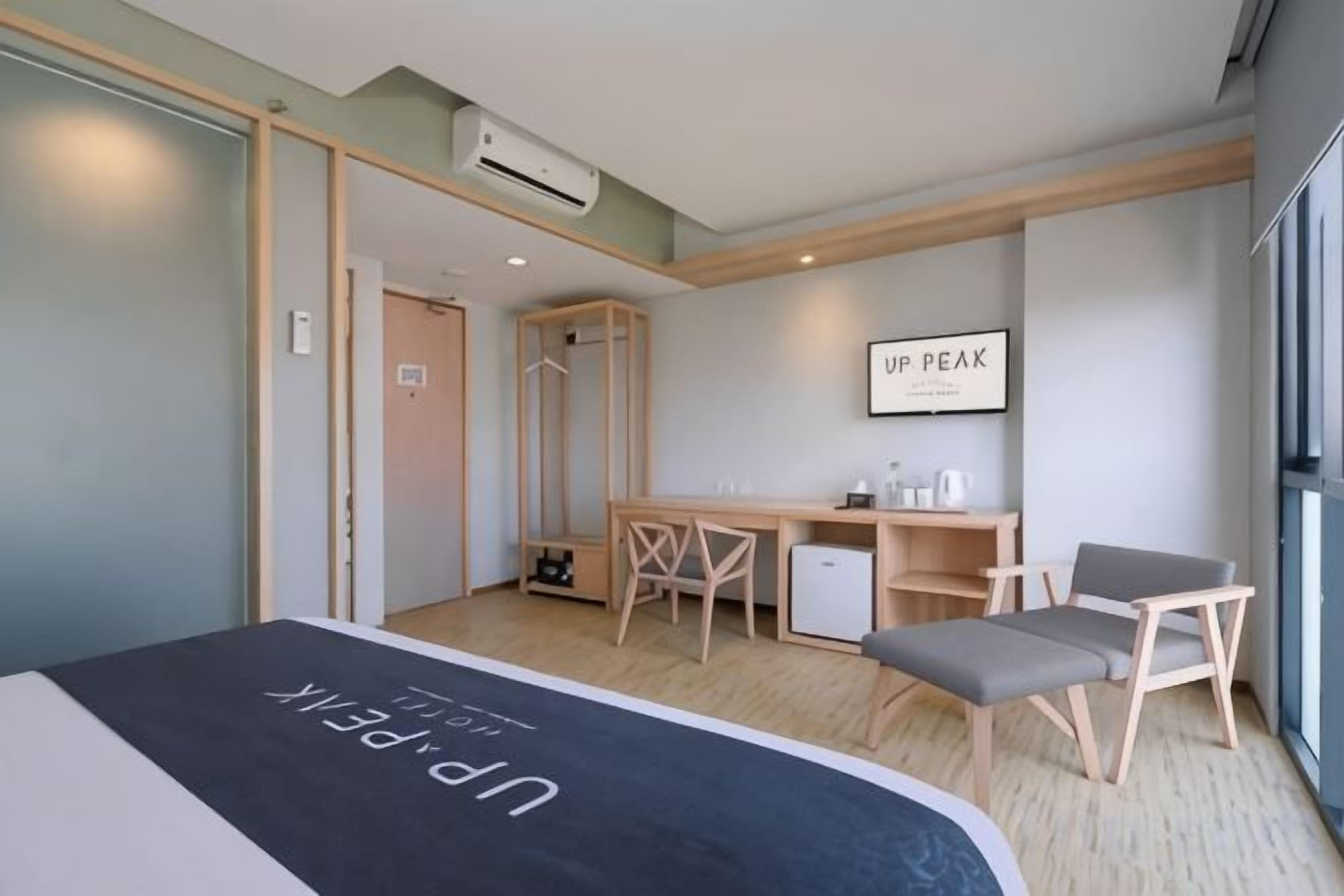 A hotel room with a bed, a desk, a chair, and a small table.