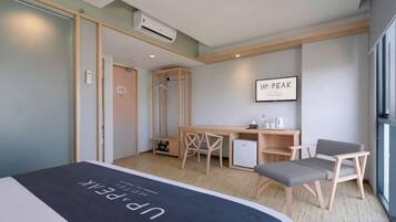 A hotel room with a bed, a desk, a chair, and a small table.