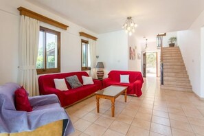 Un saló amb un sofà vermell, un sofà morat i una taula de centre de fusta.