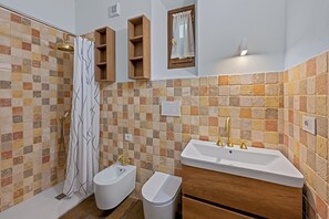 A bathroom with a shower, bidet, sink, and wooden cabinets. - Balconcini de Saracini Villa (Siena)