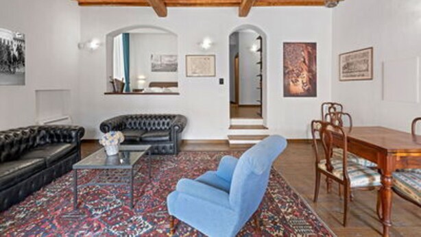 Ein Wohnzimmer mit Sofa, Sessel, Couchtisch und einem Essbereich mit Stühlen und Tisch.