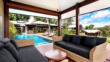 A spacious outdoor area with a pool, wicker furniture, and a view of a residential area.