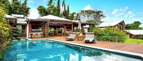 A swimming pool with lounge chairs and a covered patio area.