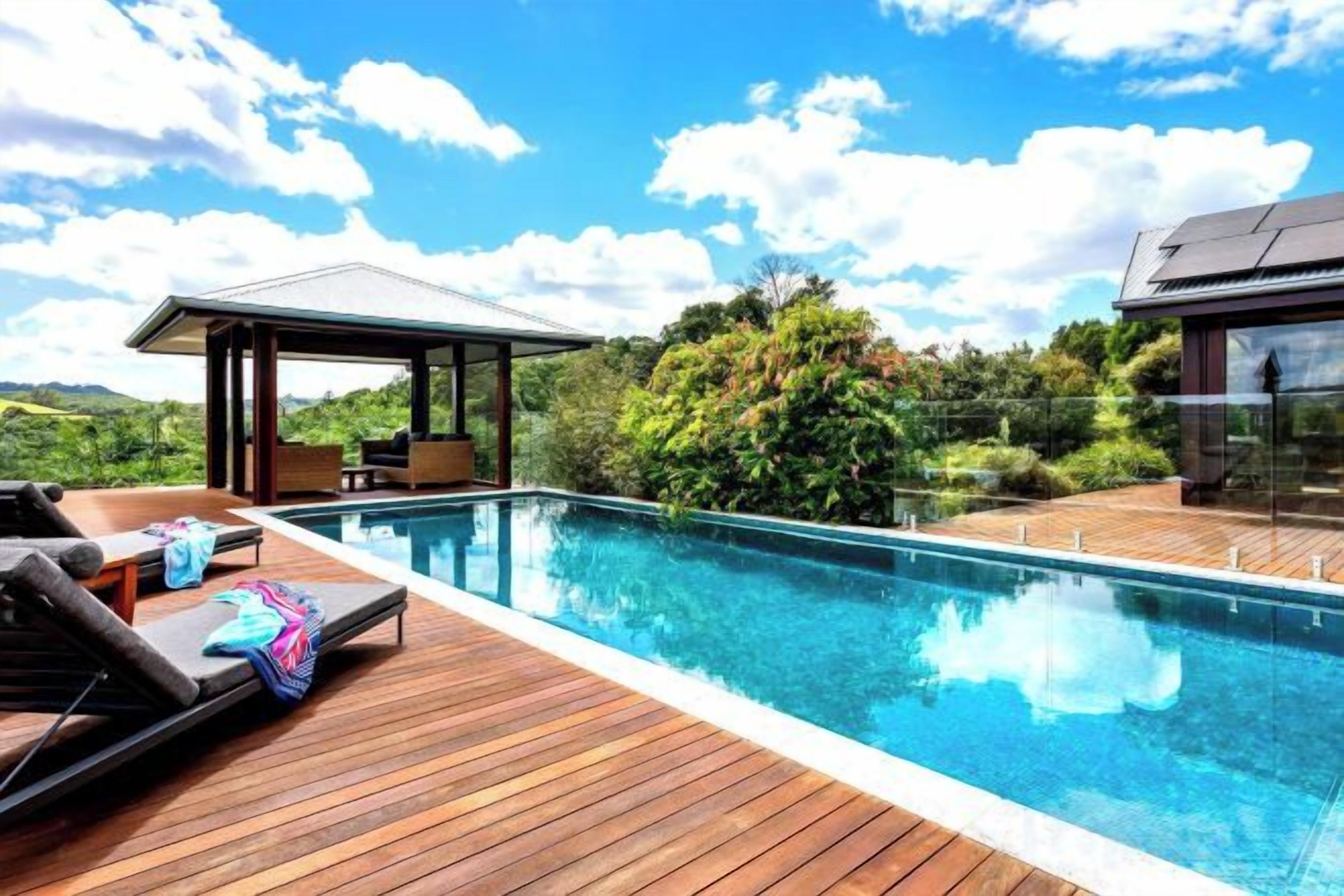 Un área junto a la piscina con sillones de descanso y una zona de estar techada.