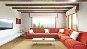 Una sala de estar moderna con un sofá seccional rojo, una mesa de centro y un ventanal con vistas al exterior.