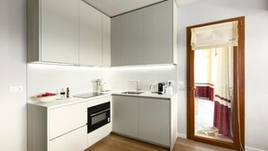 Una cocina compacta con muebles blancos, horno empotrado y lavamanos.