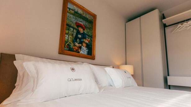 Una habitación de hotel con cama, almohadas, un cuadro y un armario.