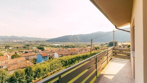 Un balcón con vista a un viñedo y montañas al fondo.