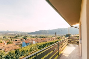 Un balcón con vista a un viñedo y montañas al fondo.