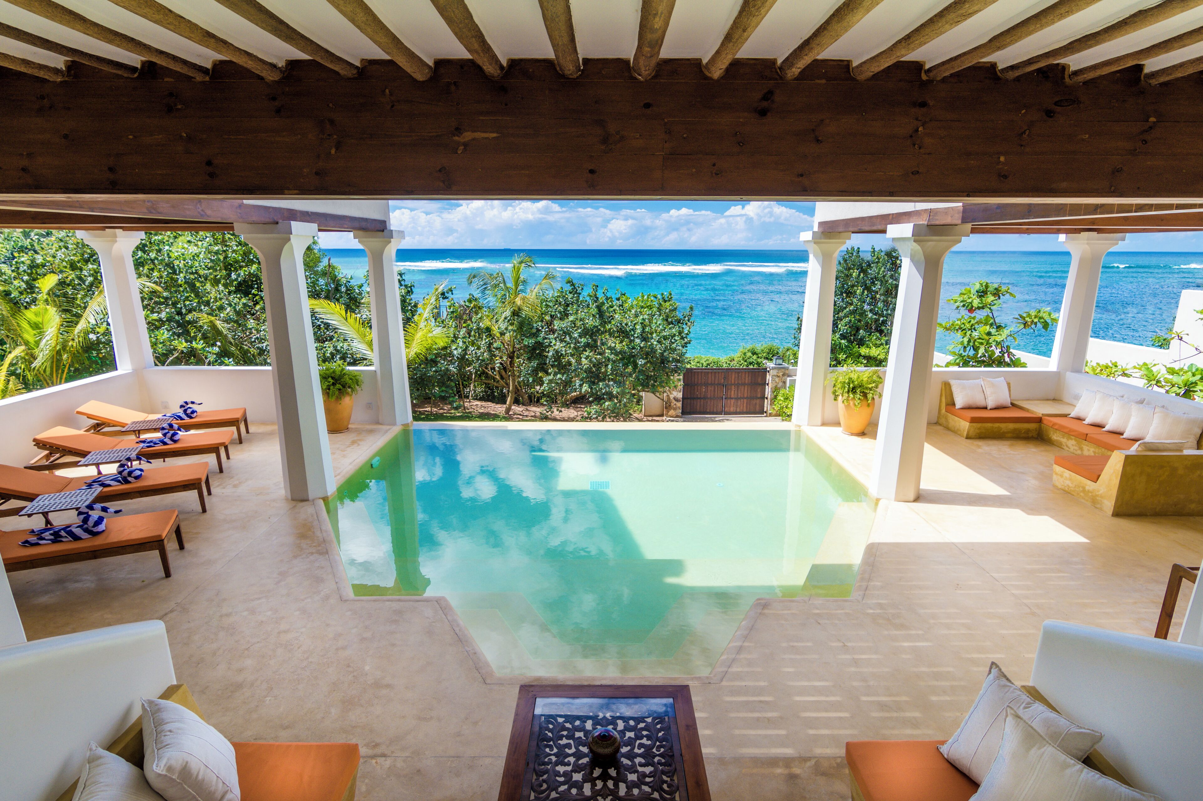 A pool area with lounge chairs and a view of the ocean.