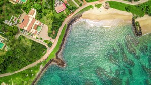 An aerial view of a coastal area with a sandy beach, a rocky shoreline, and a mix of residential buildings including a medical facility. - Cinnamon House, Weligama by The Serendipity Collection (Weligama)