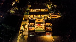 Un hotel de varios pisos con piscina, mobiliario exterior e ingreso bien iluminado.