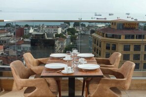 A dining table with chairs on a balcony overlooking a cityscape. - Belmond hotel (Istanbul)