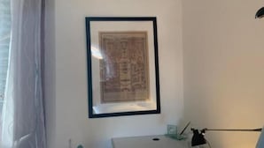 A framed map on a wall, a desk with a lamp, and a window with curtains.