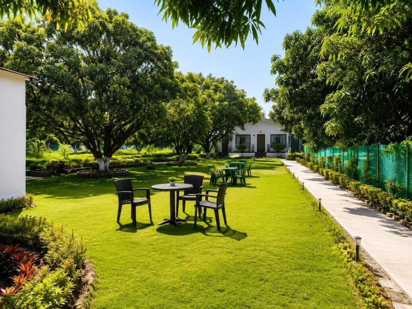 Un jardín bien cuidado con un área de descanso, un sendero y un edificio al fondo.