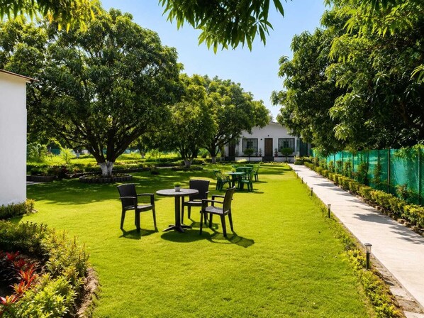 Un jardín bien cuidado con un área de descanso, un sendero y un edificio al fondo.