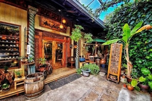 A rustic storefront with wooden architecture, a variety of potted plants, and a sign that reads "Aniba 3D".
