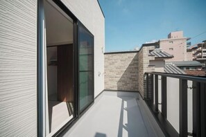 A balcony with a sliding glass door, a metal railing, and a view of neighboring buildings.