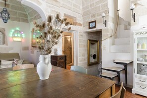 A rustic room with a wooden table, a white vase with dried plants, a mirror, and a white cabinet with shelves. - Terrazza Calipso by Wonderful Italy (Ostuni)