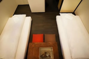 Habitació amb dos llits, una taula petita amb una fotografia i un terra endollat.