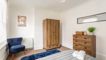 A bedroom with a bed, a wardrobe, a chair, and a radiator.