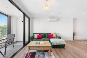Una sala moderna con un sofá verde, una mesa de centro de madera y un ventanal grande.