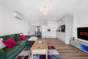A modern living room with a green sofa, a wooden coffee table, and a TV displaying the Netflix logo. - Flat 2, Brentford TW8 9NA (Brentford)