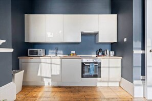 Eine moderne Küche mit weißen Schränken, einer Mikrowelle, einem Spülbecken und einem eingebauten Backofen.