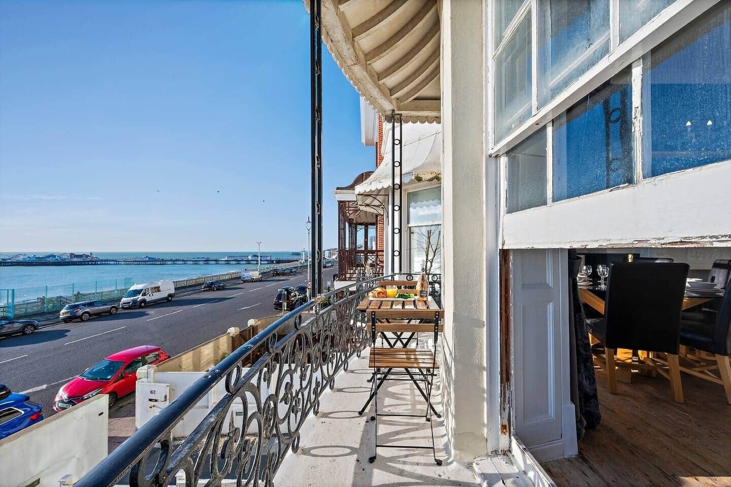 A balcony with a view of the sea and a road with vehicles.