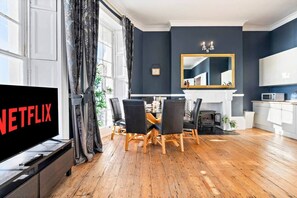 A modern living room with a dining area, a fireplace, and a television displaying the Netflix logo. - 68 Marine Parade - BN2 1AD (Brighton and Hove)