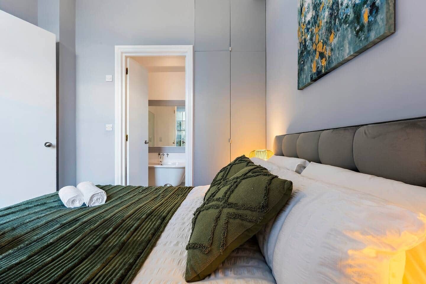 Ein Hotelzimmer mit einem Bett, einem durchgegangenen Tür erkennbaren Badezimmer und einem Bild an der Wand.